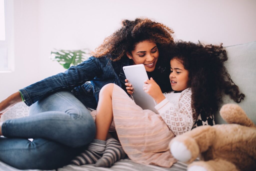 como retirar sobrenome paterno - filha usando um tablet com a mãe deitada ao seu lado